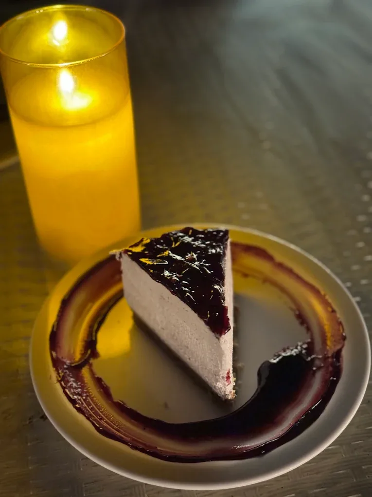 Anniversary cheesecake with a lit candle for a lakeside celebration in Pawna