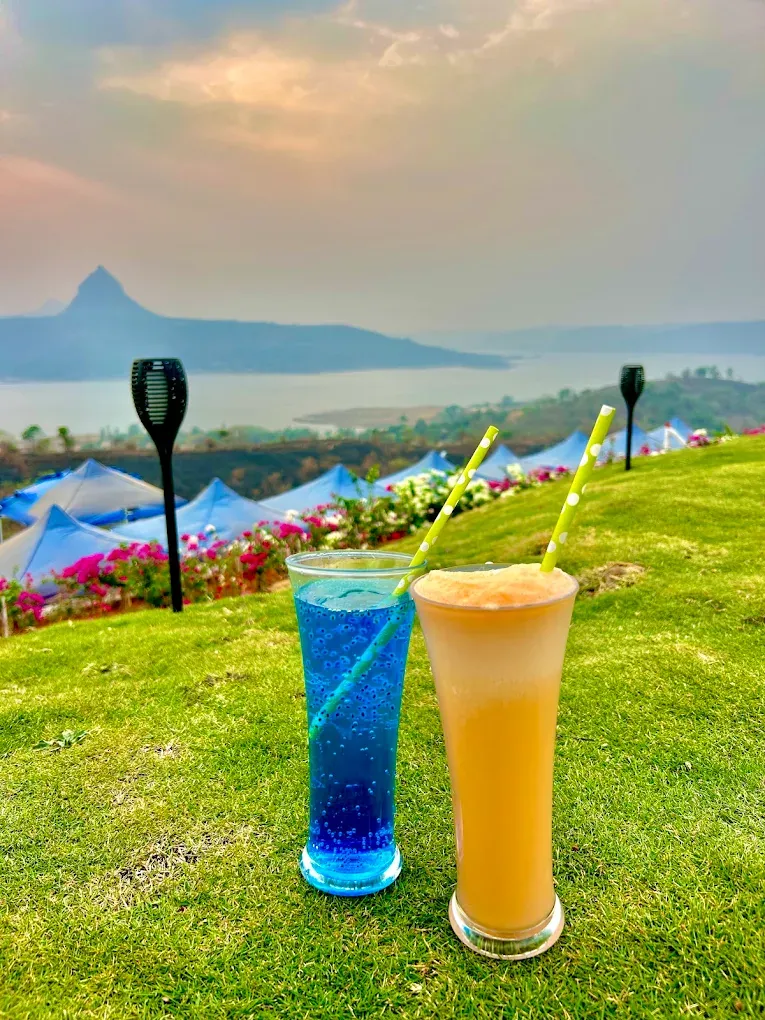 Two mocktails on the lawn overlooking Pawna Lake and mountains